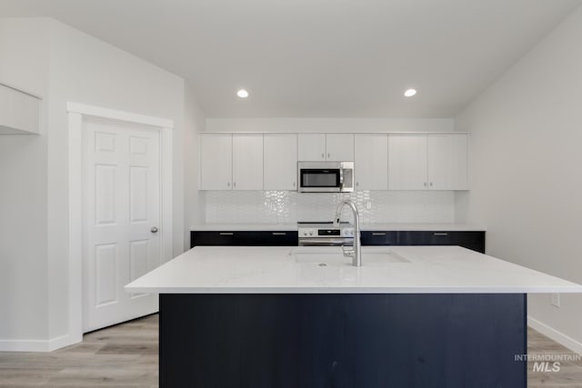 kitchen with baseboards, backsplash, light wood finished floors, and appliances with stainless steel finishes