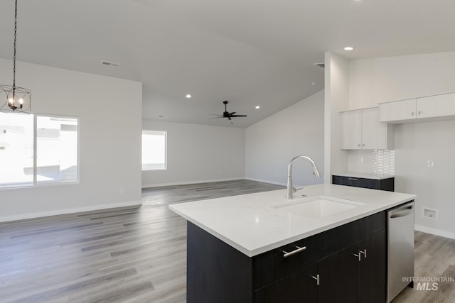 kitchen featuring dark cabinets, light countertops, a sink, dishwasher, and light wood-style floors