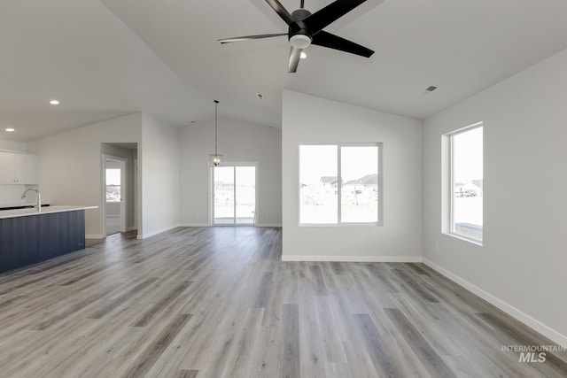 unfurnished living room with light wood finished floors, plenty of natural light, vaulted ceiling, and recessed lighting