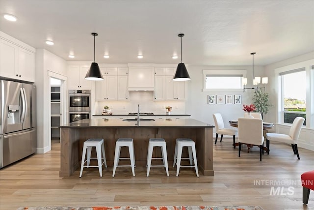 499 S Short Ln, Eagle, ID 83616 - kitchen with stainless steel appliances, dark countertops, light wood-style floors, white cabinets, and a kitchen bar