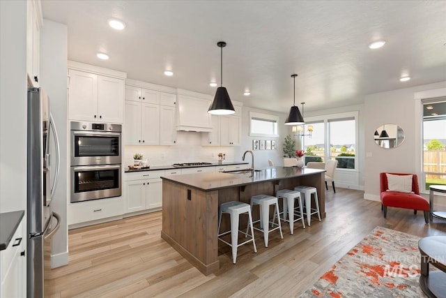 499 S Short Ln, Eagle, ID 83616 - kitchen with appliances with stainless steel finishes, light wood-type flooring, healthy amount of natural light, a kitchen breakfast bar, and recessed lighting