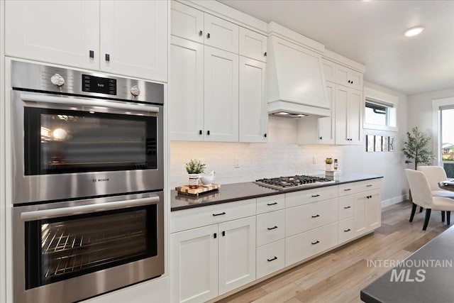 499 S Short Ln, Eagle, ID 83616 - kitchen with appliances with stainless steel finishes, light wood-style floors, dark countertops, tasteful backsplash, and white cabinets