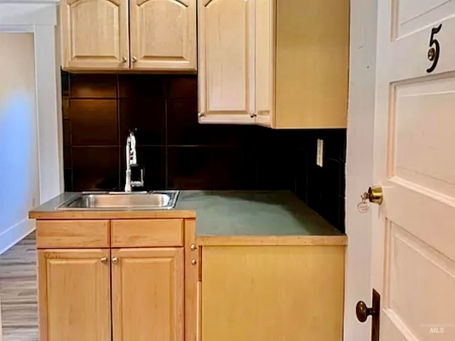 kitchen with tasteful backsplash, sink, light brown cabinetry, and hardwood / wood-style flooring