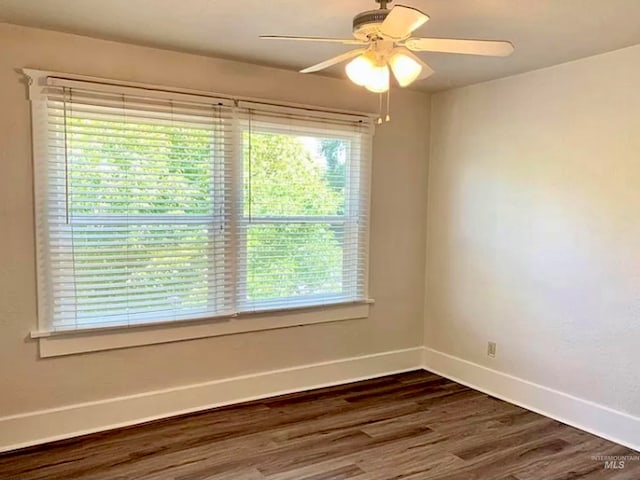 empty room with ceiling fan, dark wood-type flooring, and a wealth of natural light