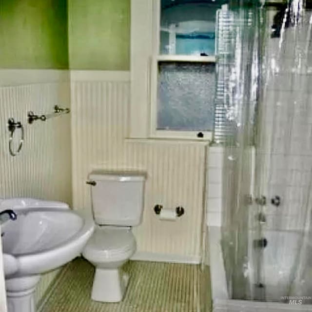 bathroom with tile patterned flooring, toilet, and tiled shower