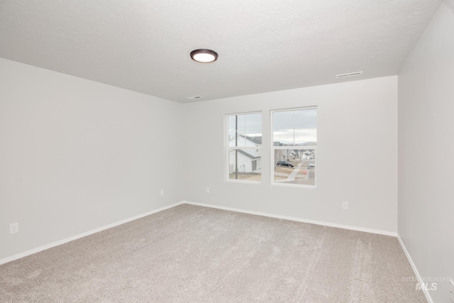 carpeted empty room featuring a textured ceiling