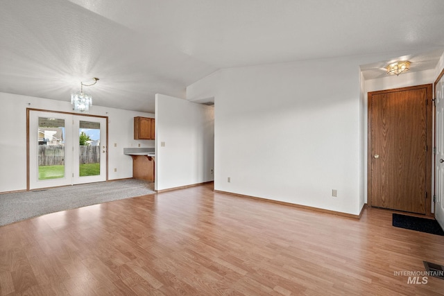 607 S State, Nampa, ID 83686 - unfurnished living room with a chandelier, light wood finished floors, lofted ceiling, and baseboards