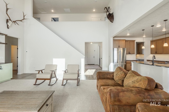 living room featuring a towering ceiling, light hardwood / wood-style floors, and sink