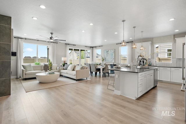 kitchen featuring a kitchen island, ceiling fan, white cabinetry, stainless steel dishwasher, and light hardwood / wood-style floors