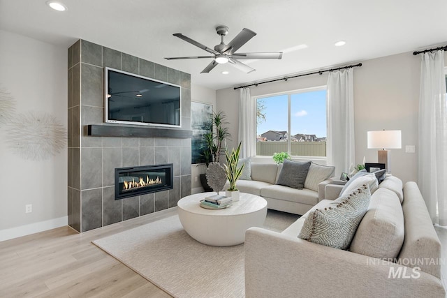 living room featuring a tile fireplace, tile walls, wood-type flooring, and ceiling fan