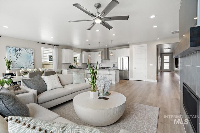 living room featuring ceiling fan, a fireplace, and light hardwood / wood-style floors