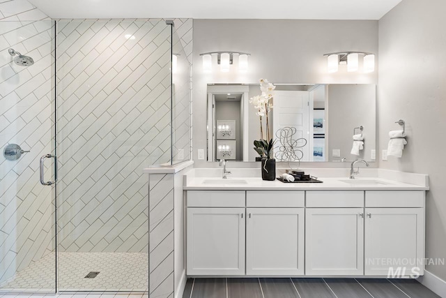 bathroom with a shower with door and dual vanity