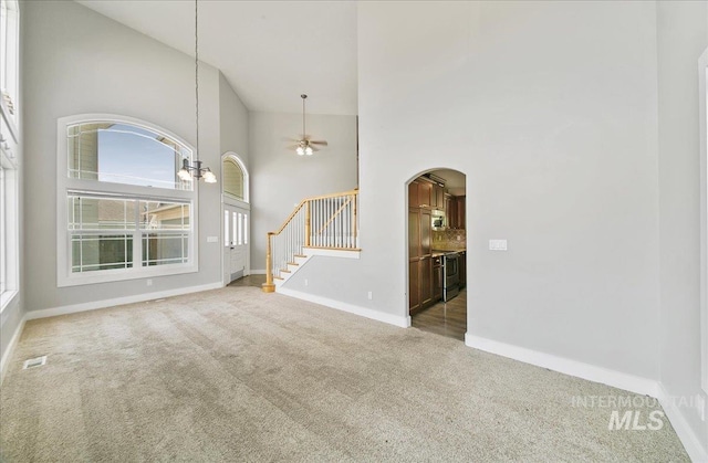 10539 W Merab Ct, Star, ID 83669 - unfurnished living room with high vaulted ceiling, carpet, arched walkways, stairs, and ceiling fan