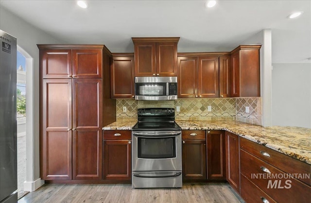 10539 W Merab Ct, Star, ID 83669 - kitchen with stainless steel appliances, reddish brown cabinets, light wood finished floors, backsplash, and recessed lighting