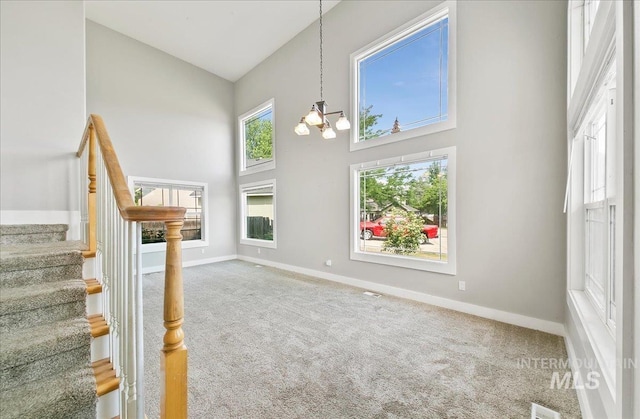 10539 W Merab Ct, Star, ID 83669 - unfurnished living room with a towering ceiling, carpet flooring, stairway, and a chandelier