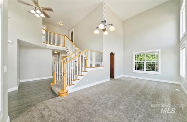 10539 W Merab Ct, Star, ID 83669 - unfurnished living room with a high ceiling, arched walkways, stairway, a ceiling fan, and a chandelier