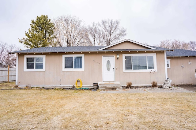 view of front of property featuring entry steps, a front lawn, roof with shingles, and fence