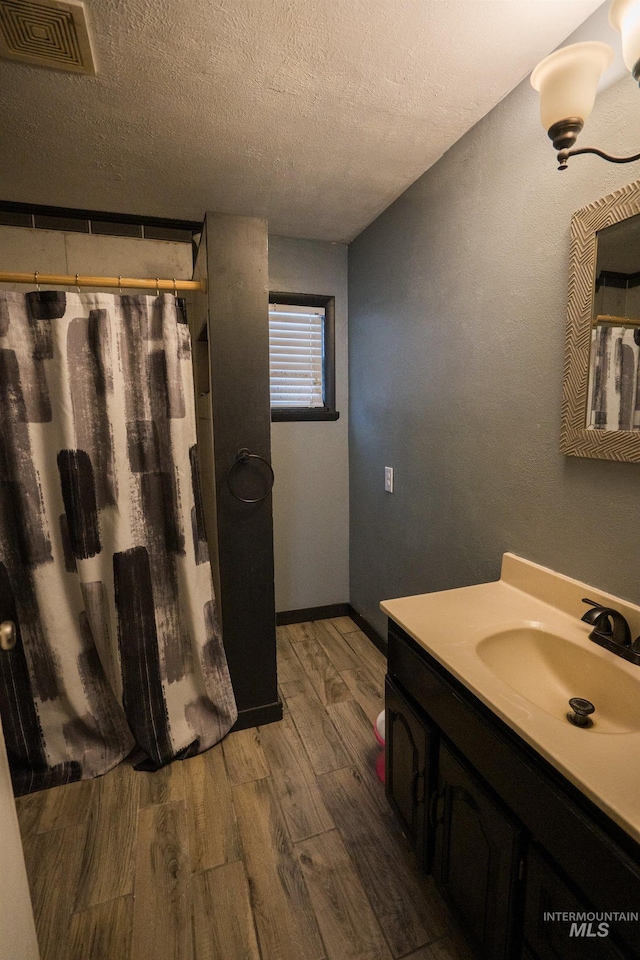 full bath featuring visible vents, a textured ceiling, vanity, wood finished floors, and a shower with curtain