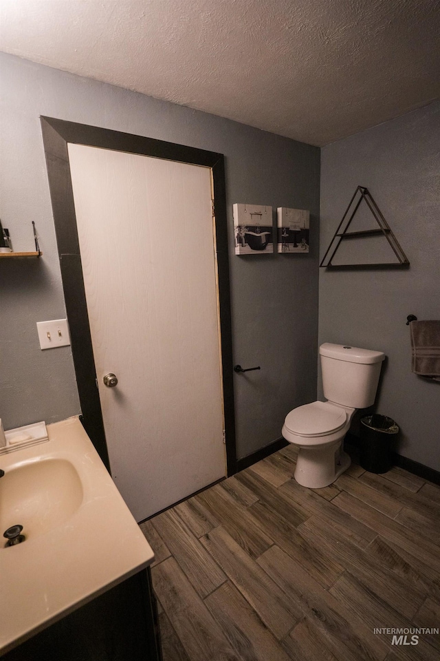 bathroom featuring vanity, a textured ceiling, toilet, and wood finished floors