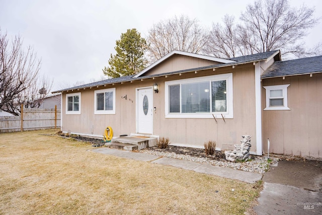 view of front of home with a front lawn, roof with shingles, and fence