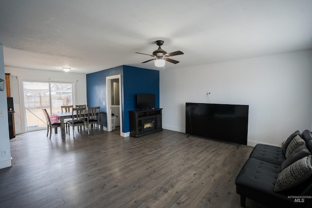 living room with a fireplace, baseboards, and wood finished floors