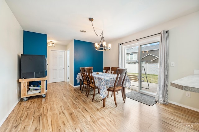 dining space featuring baseboards, light wood-type flooring, and an inviting chandelier