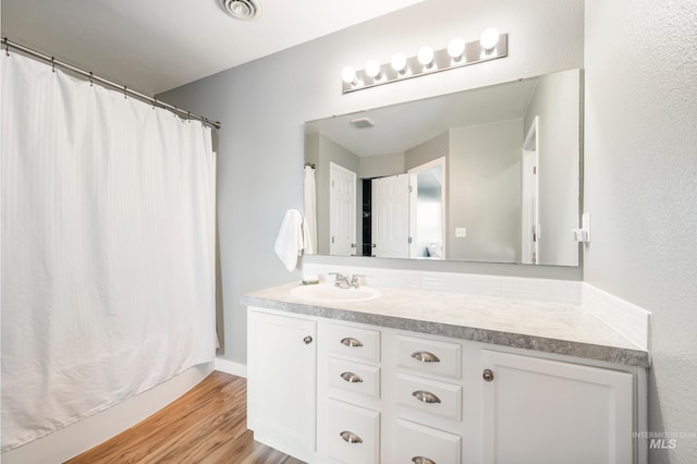 full bathroom featuring visible vents, vanity, a shower with curtain, and wood finished floors