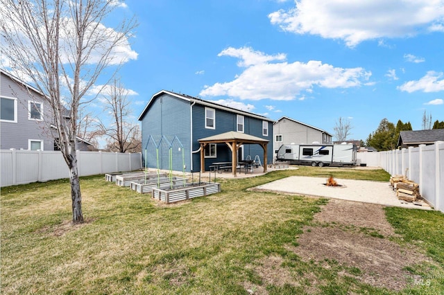 rear view of house with an outdoor fire pit, a vegetable garden, a gazebo, a patio area, and a lawn