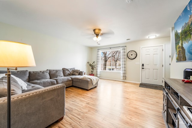 living area featuring baseboards, light wood-style flooring, and a ceiling fan