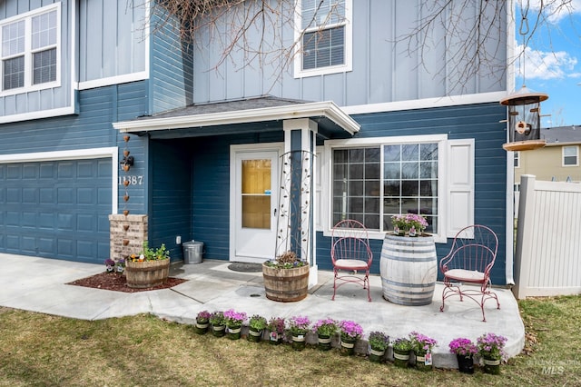 entrance to property featuring a patio, a garage, fence, and board and batten siding