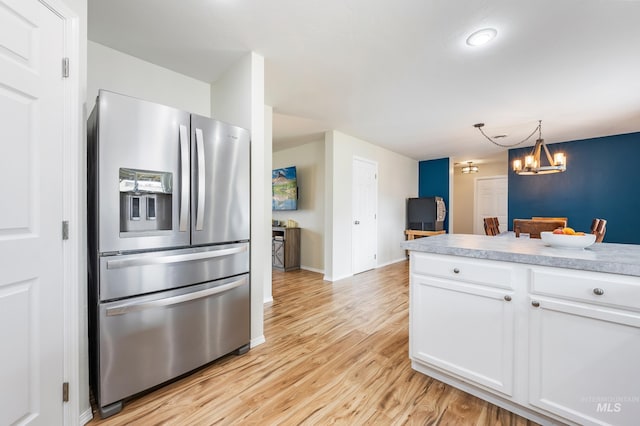 kitchen with light wood-style flooring, white cabinetry, stainless steel fridge with ice dispenser, light countertops, and a chandelier