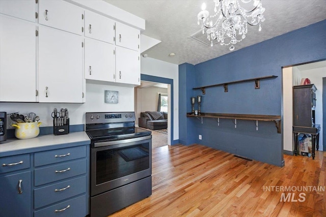 720 E Center St, Kimberly, ID 83341 - kitchen with electric range, white cabinets, light countertops, a chandelier, and light wood-style flooring