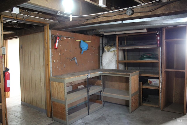 basement with a workshop area and wooden walls