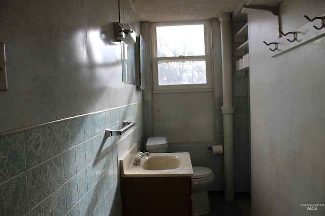 bathroom with tile walls, toilet, and vanity