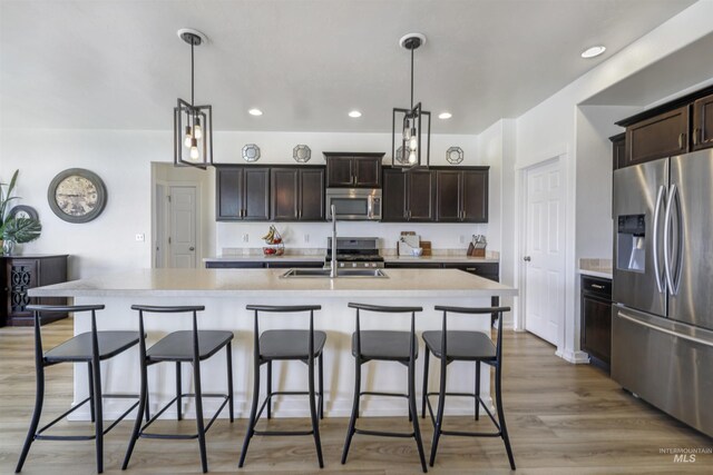 kitchen featuring light wood-style flooring, dark brown cabinets, appliances with stainless steel finishes, light countertops, and a sink