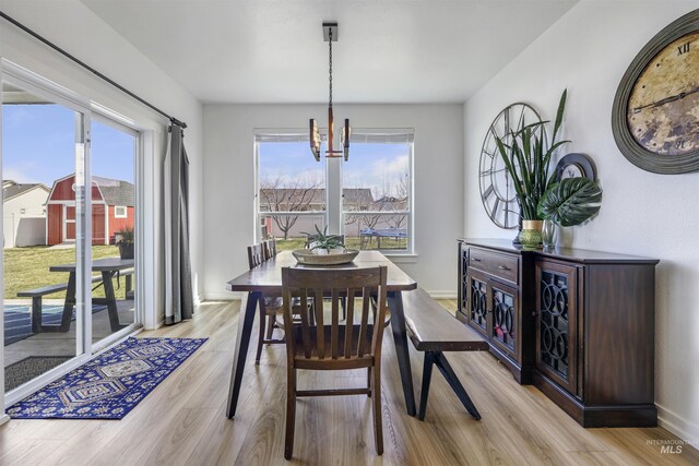dining room with a notable chandelier, light wood-type flooring, and baseboards