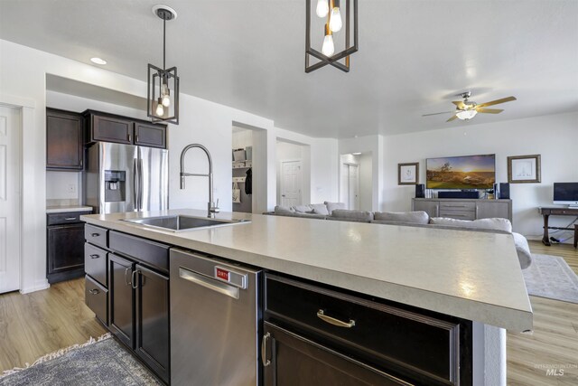 kitchen with stainless steel appliances, open floor plan, a sink, and ceiling fan