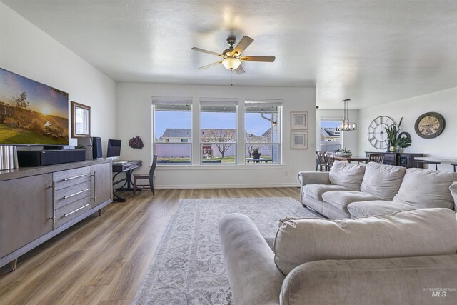 living room with ceiling fan, baseboards, and wood finished floors