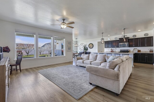 living area with light wood-style flooring, recessed lighting, ceiling fan, and baseboards