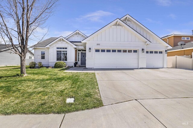 modern farmhouse style home featuring concrete driveway, board and batten siding, a front lawn, a garage, and fence