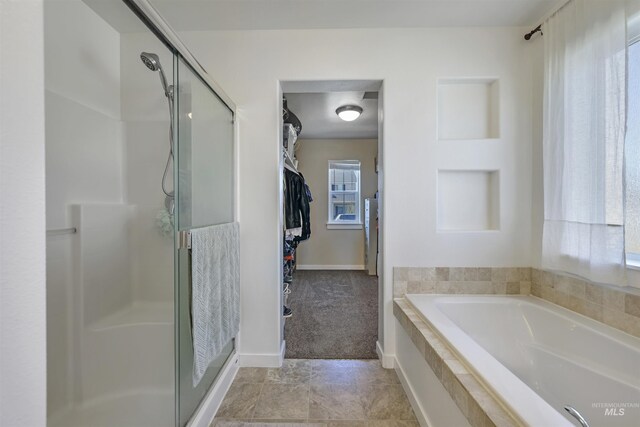 bathroom with a walk in closet, a bath, and a shower stall