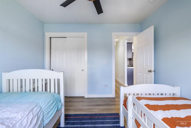 bedroom featuring a closet, baseboards, a ceiling fan, and wood finished floors
