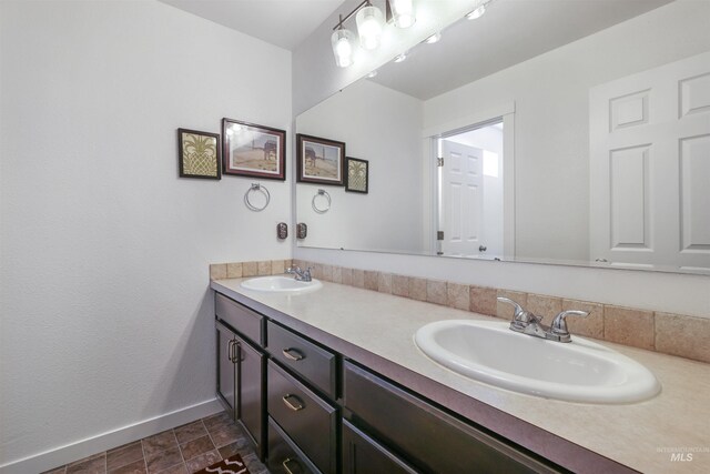 bathroom featuring a sink, baseboards, and double vanity