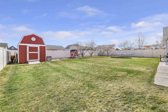 view of yard featuring an outbuilding, a fenced backyard, a trampoline, and a shed