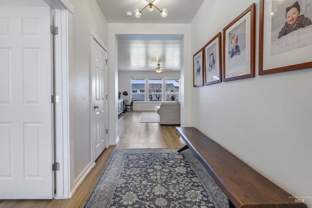 corridor with an inviting chandelier and wood finished floors