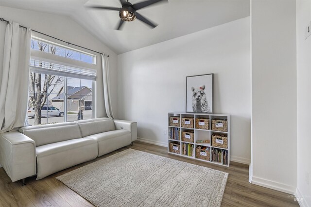 living room featuring wood finished floors, baseboards, a ceiling fan, and vaulted ceiling