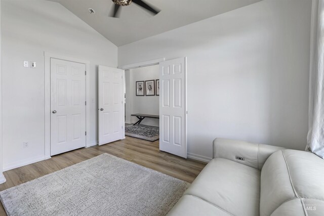 living area with wood finished floors, ceiling fan, baseboards, and vaulted ceiling