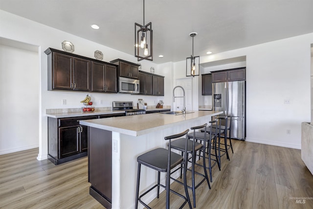 kitchen with stainless steel appliances, dark brown cabinetry, light countertops, and a sink