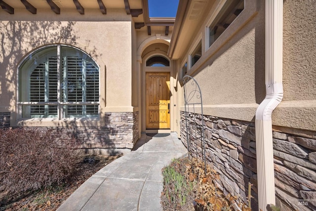 view of exterior entry with stucco siding and stone siding