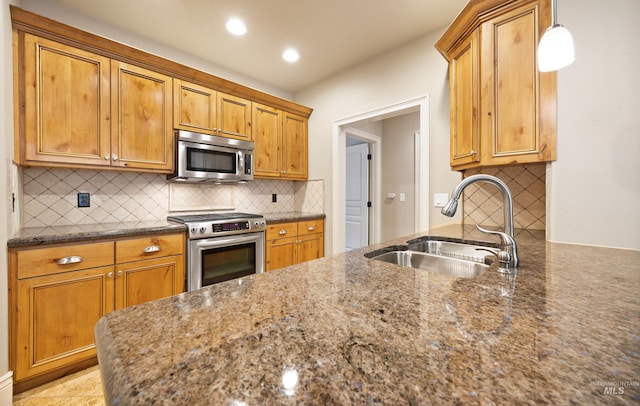 kitchen with a sink, dark stone countertops, tasteful backsplash, recessed lighting, and appliances with stainless steel finishes